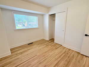 Unfurnished bedroom featuring light wood finished floors, a closet, and baseboards