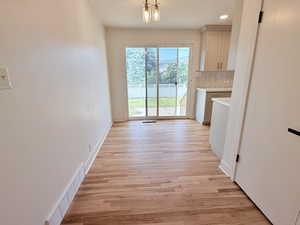 Unfurnished dining area with light wood finished floors, baseboards, and recessed lighting