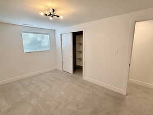 Unfurnished bedroom featuring light carpet, a closet, and baseboards