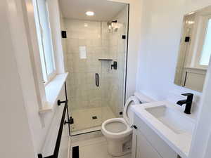 Bathroom featuring toilet, vanity, a stall shower, tile patterned floors, and recessed lighting
