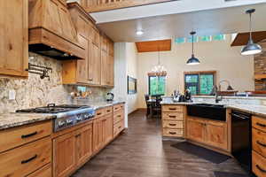 Kitchen with custom range hood, a sink, black dishwasher, stainless steel gas stovetop, and tasteful backsplash