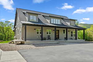 View of front of house featuring board and batten siding, a porch, metal roof, and a standing seam roof