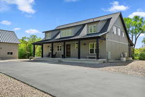Modern inspired farmhouse with a porch, metal roof, board and batten siding, a standing seam roof, and central air condition unit