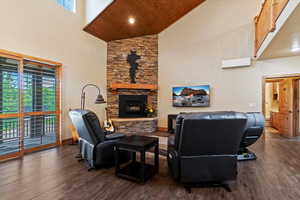 Living room with high vaulted ceiling, dark wood-style flooring, plenty of natural light, wood ceiling, and a stone fireplace