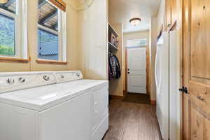 Washroom featuring independent washer and dryer, dark wood-style floors, and baseboards