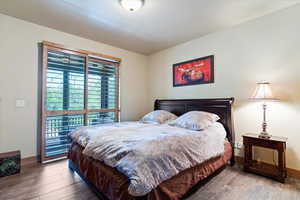 Bedroom with wood finished floors, access to exterior, and baseboards