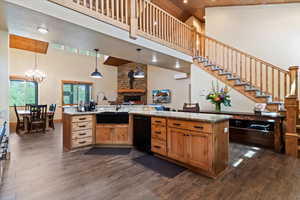 Kitchen featuring high vaulted ceiling, black dishwasher, a sink, dark wood-style floors, and a fireplace