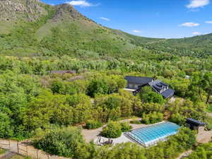 Aerial view of property and surrounding area featuring a heavily wooded area and a mountain backdrop