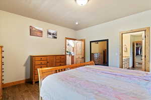 Bedroom with wood finished floors, baseboards, and connected bathroom