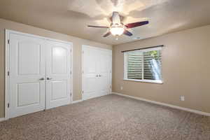 Unfurnished bedroom featuring carpet flooring, a textured ceiling, baseboards, and a ceiling fan