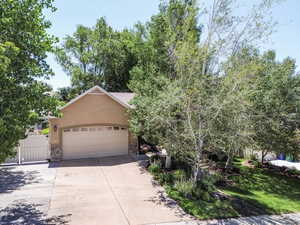 Obstructed view of property featuring stone siding, stucco siding, driveway, and an attached garage