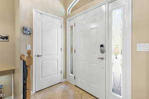 Entryway with light tile patterned floors and baseboards