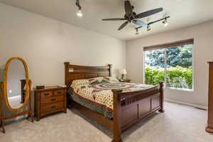 Bedroom with rail lighting, light carpet, baseboards, and a ceiling fan
