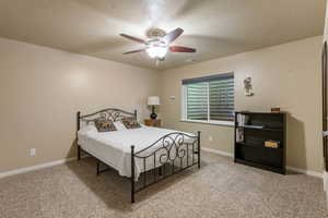 Bedroom featuring a textured ceiling, carpet, baseboards, and a ceiling fan