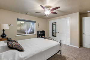 Carpeted bedroom with a textured ceiling, baseboards, and ceiling fan