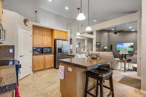 Kitchen featuring appliances with stainless steel finishes, a sink, tile counters, a breakfast bar area, and open floor plan