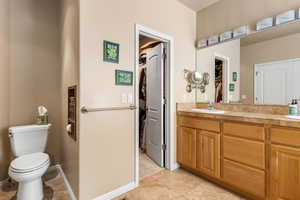 Bathroom featuring a spacious closet, double vanity, toilet, tile patterned floors, and baseboards