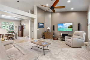 Carpeted living area with recessed lighting, ceiling fan, baseboards, and a high ceiling