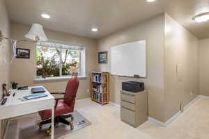 Office space featuring a textured ceiling, light carpet, recessed lighting, and baseboards
