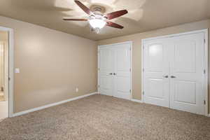 Unfurnished bedroom with carpet flooring, baseboards, a ceiling fan, a textured ceiling, and a closet