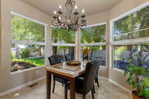 Sunroom featuring baseboards, a chandelier, and tile patterned floors