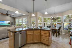 Kitchen featuring stainless steel dishwasher, a sink, tile countertops, ceiling fan, and hanging light fixtures