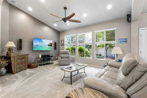 Carpeted living room featuring vaulted ceiling, a ceiling fan, baseboards, and recessed lighting