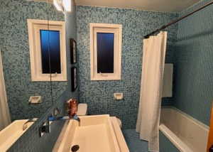 Full bath featuring tile walls, toilet, shower / bathtub combination with curtain, and vanity