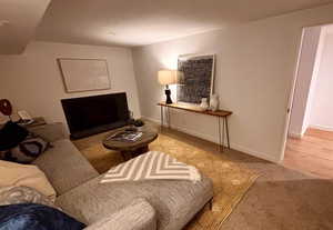 Living room with a fireplace, baseboards, and carpet flooring