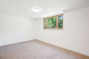 Carpeted spare room featuring baseboards
