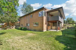 Rear view of house featuring a yard and a balcony