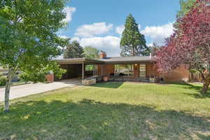 View of front facade featuring an attached carport, a front lawn, and driveway