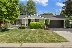 Ranch-style house featuring a garage, a front lawn, driveway, a shingled roof, and a porch
