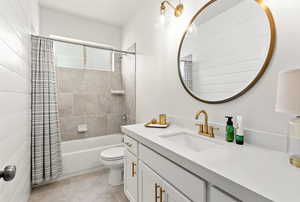 Main bathroom with vanity, shower/ bath combo, toilet, shiplap wall and tile patterned floors