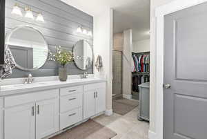 Master bathroom featuring double vanity, tile shower, glass enclosure, tile patterned flooring, a spacious walk-in closet