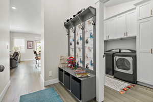 Mudroom featuring washer and dryer, light engineered hardwood flooring, and recessed lighting