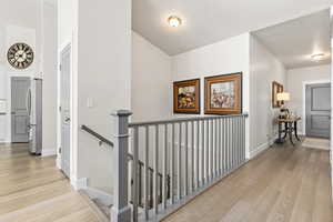 Hall featuring front door an upstairs landing, light engineered hardwood flooring
