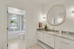 Bathroom featuring vanity, marble finish floors, and a bathtub
