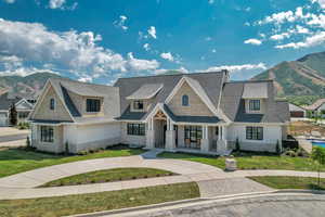 Shingle-style home featuring stone siding, a mountain view, covered porch, and a shingled roof