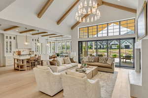 Living area featuring beam ceiling, a chandelier, light wood finished floors, a towering ceiling, and recessed lighting