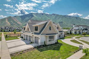 View of front of house featuring an attached garage, concrete driveway, a mountain view, and a residential view