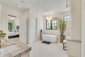 Ensuite bathroom with double vanity, a freestanding tub, a chandelier, tile patterned flooring, and recessed lighting