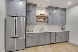 Kitchen with freestanding refrigerator, gray cabinetry, light countertops, decorative backsplash, and recessed lighting