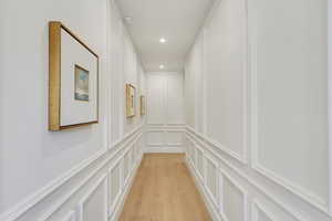 Corridor featuring a decorative wall, light wood-style floors, and recessed lighting