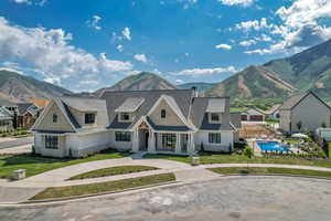 Shingle-style home featuring a mountain view, a front yard, and roof with shingles