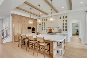 Kitchen featuring arched walkways, open shelves, double oven, light wood-type flooring, and a kitchen bar