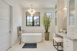 Bathroom with plenty of natural light, a freestanding bath, a chandelier, and vanity