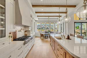 Kitchen with a sink, wooden ceiling with exposed beams, plenty of natural light, light countertops, and light wood-style flooring