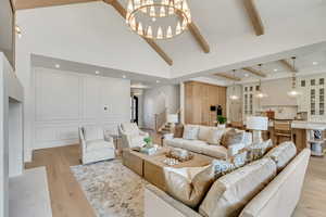 Living room with high vaulted ceiling, beam ceiling, a chandelier, light wood-style floors, and arched walkways