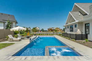 View of pool featuring a patio, a residential view, a fenced backyard, and a pool with connected hot tub